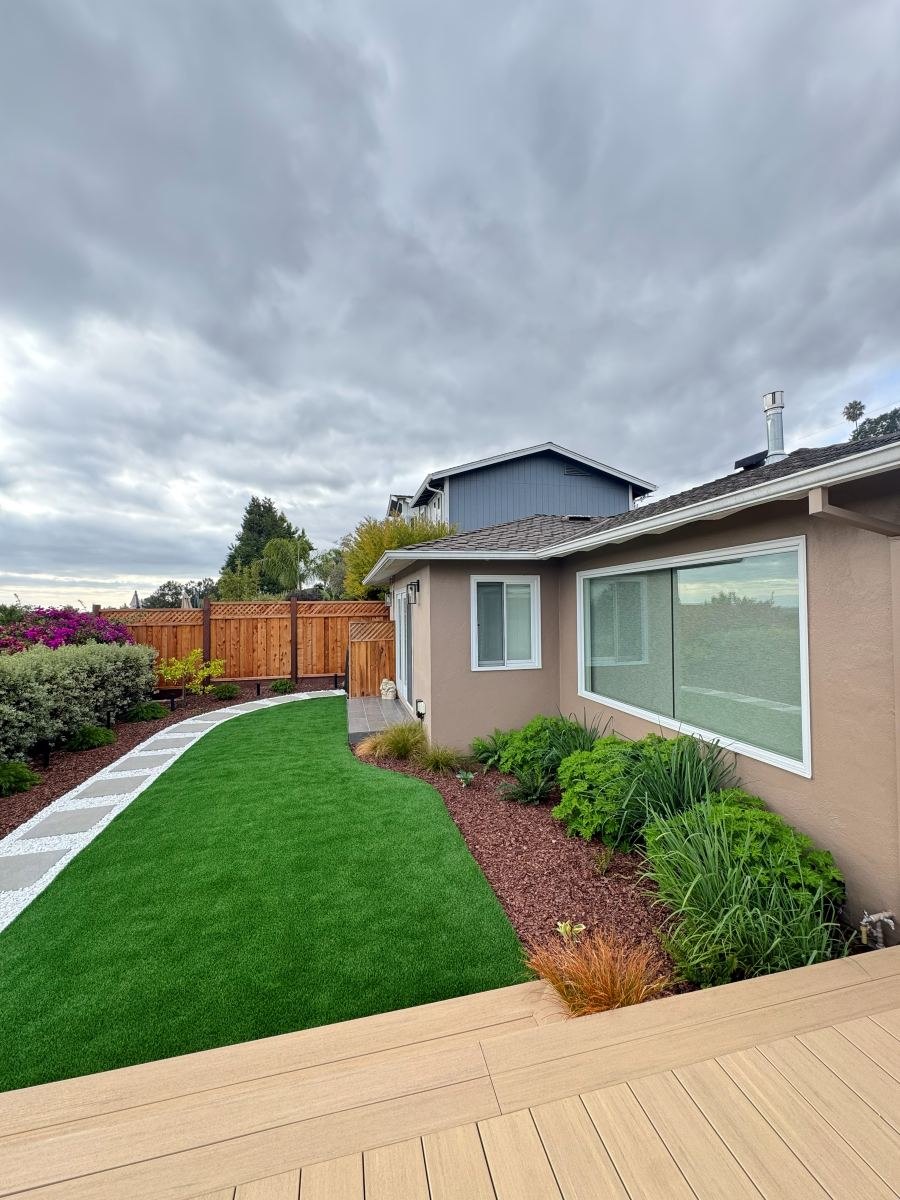 Backyard landscaping with artificial turf, planting beds and composite deck