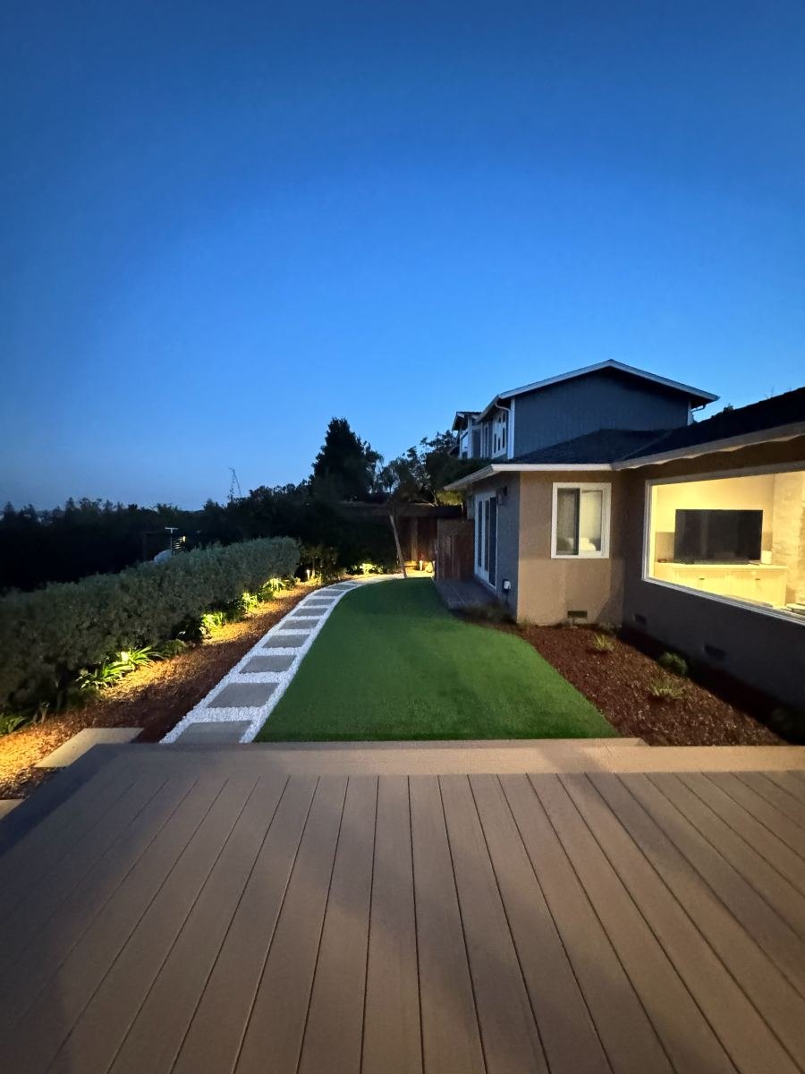 Composite deck and turf lawn with landscape lighting at dusk
