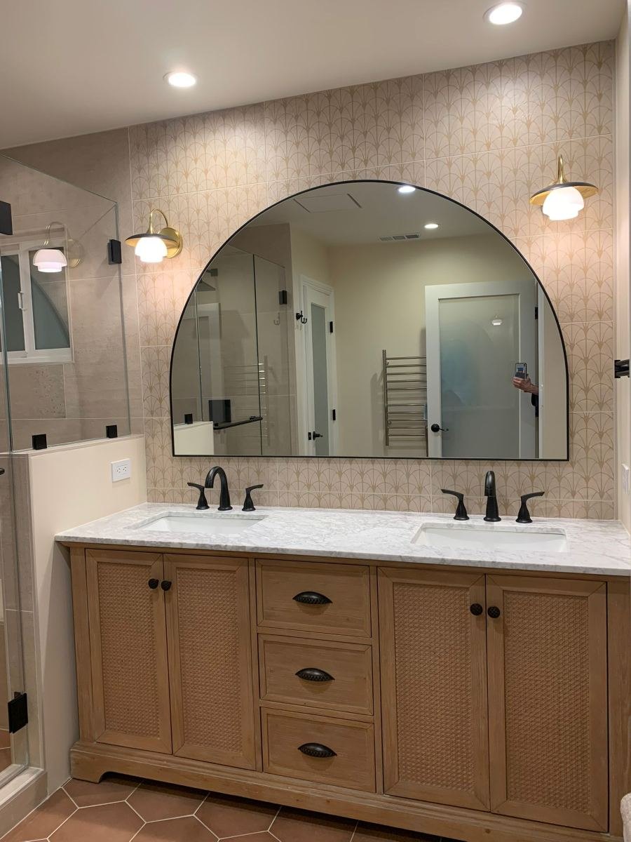Bathroom remodel with wood double vanity and arched mirror