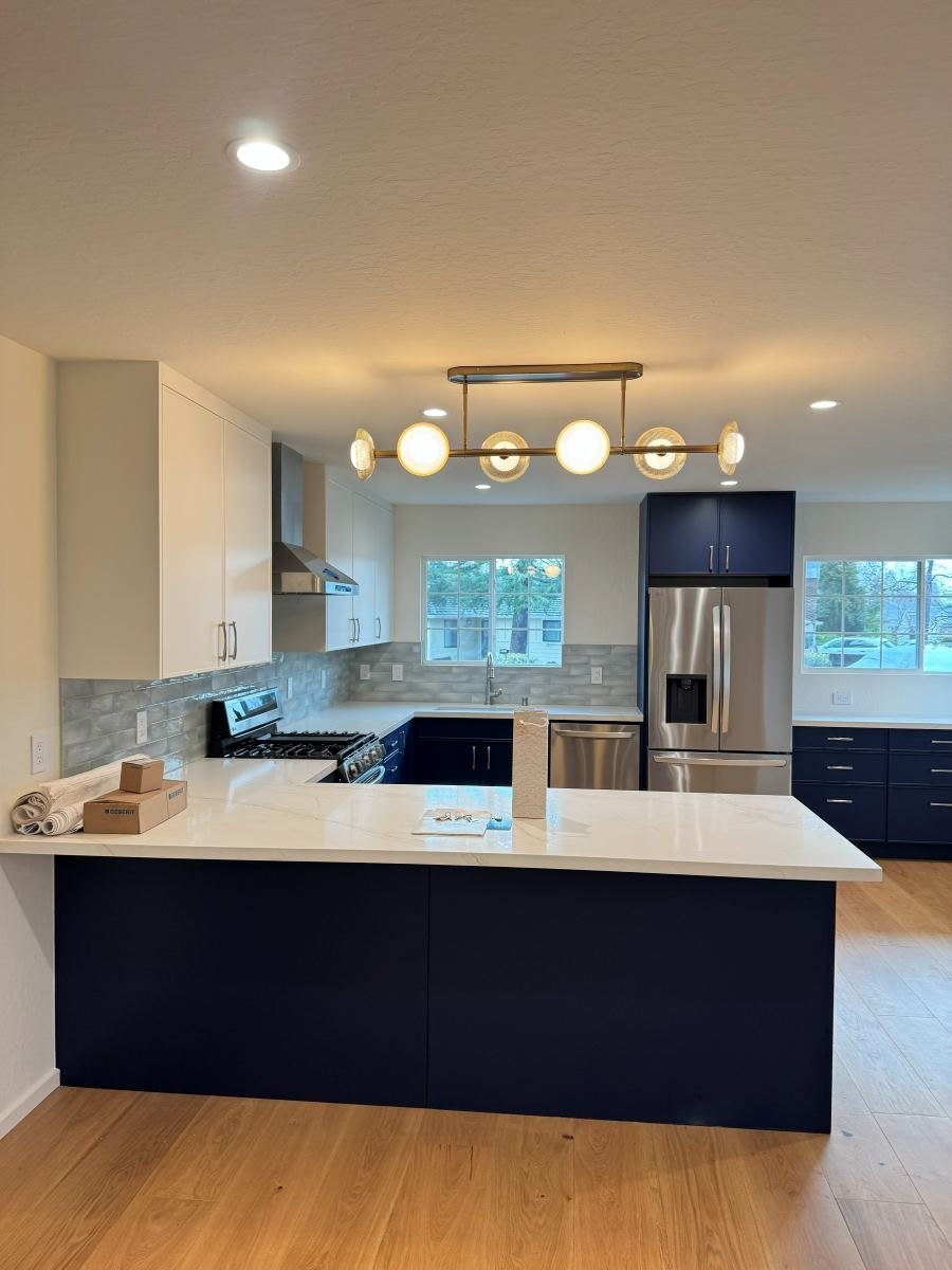 Open kitchen remodel with navy cabinets and globe pendant light