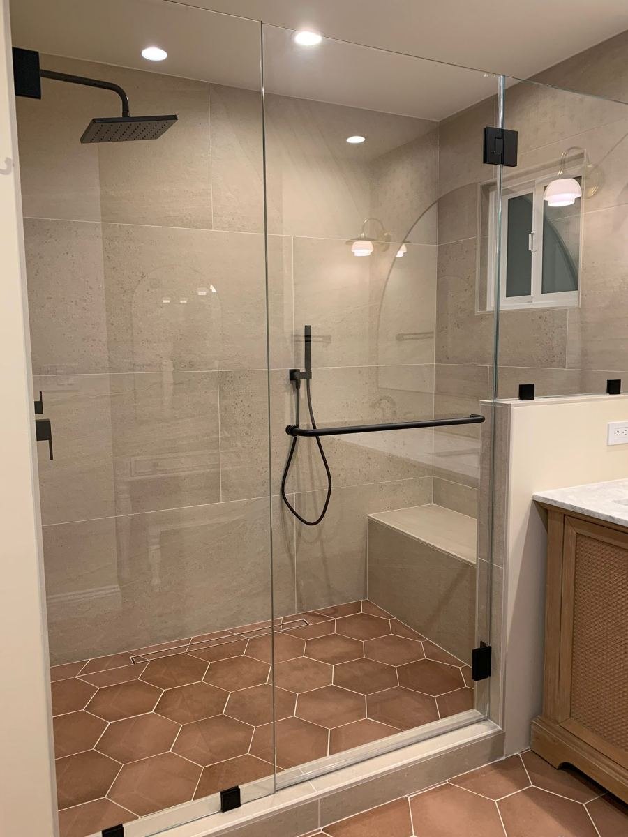 Walk-in shower with frameless glass, bench and terracotta hex tile floor